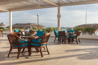 Hasır sandalyeler ve turkuaz yastıklı masalar misafirleri Marsa Alam, Mısır 'da deniz kenarında bir terasa davet ediyor.