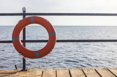 Marsa alam, Mısır 'da arka planda deniz olan bir tırabzanda asılı duran turuncu can simidi, yüzücülerin güvenliğini ve güvenliğini sağlıyor.