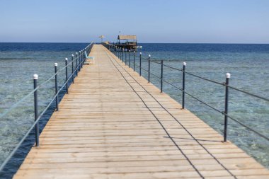 Ahşap iskele, güneş şemsiyesi ve taraçayla bir platforma ulaşıyor. Kızıl denizde, Marsa Alam, Mısır.