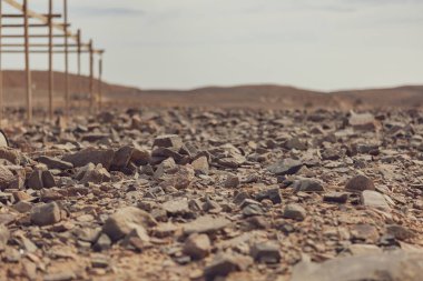 Mars çölünün kurak zeminini kaplayan kayalar, arka planda bulanık ahşap bir yapı ile Marsa alam