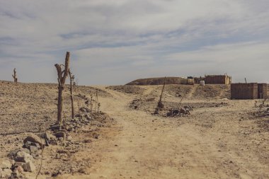 Marsa Alam, Mısır yakınlarındaki ıssız bir çöl manzarasında, yoksulluğu ve kıtlığı vurgulayan bir grup tehlikeli eve giden yol.