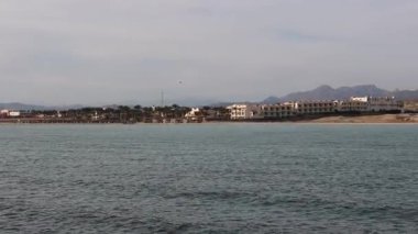 Panoramik hava manzarası Marsa Alam sahil şeridini gösteriyor. Çöl dağları ve geniş kızıl deniz suları arasında yerleşmiş lüks otel kompleksleri var.