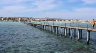 Marsa Alam, Mısır 'daki turistik kıyı şeridine karşı kızıl denizin turkuaz sularını aşan yalnız bir turist, sakin tropikal manzarayı yakalıyor.