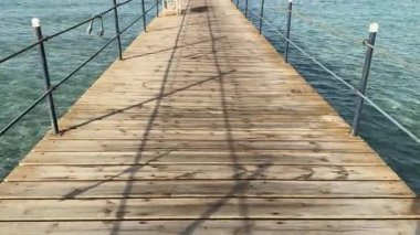 Turkuaz sudan geçerek Marsa Alam, Mısır 'daki bir tatil köyüne doğru uzanan uzun tahta iskele huzurlu ve davetkar bir sahne sunuyor.