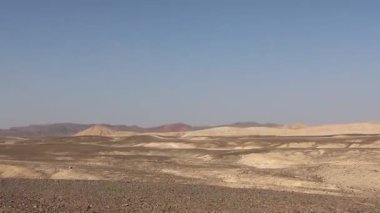 Geniş, düz, kayalık çöl arazisi uzak dağlara doğru uzanır açık mavi gökyüzü altında Marsa alam, Mısır 'da