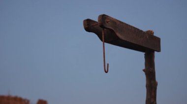 Eski ahşap kirişten sarkan paslı metal kanca Marsa alam çölünün açık mavi gökyüzüne karşı kırsal Mısır mimari detaylarını gözler önüne seriyor.