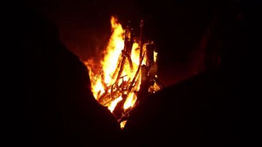 Yanıp sönen şenlik ateşi, Marsa Alam, Mısır yakınlarındaki karanlık çöl gecesine sıcak ışık tutuyor. Parlayan közler ve dans eden alevlerle çevresini aydınlatıyor.