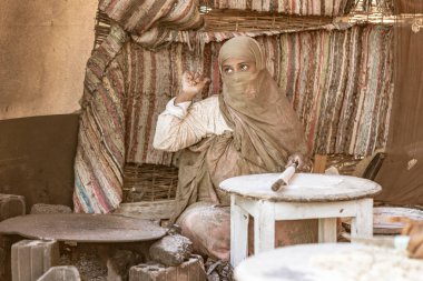 Marsa alam, Mısır 9 Şubat 2025: Marsa alam çölündeki kadın geleneksel ekmeği ustalıkla yapıyor, kırsal malzemeler ve dokuma bir zemin ile çevrili, kültürel mirası gözler önüne seriyor.