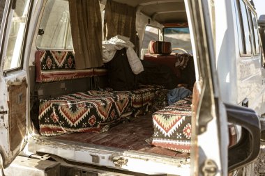 Marsa alam, Mısırın 9 Şubat 2025: desenli koltukları ve açık kapısı olan klasik minibüs iç mekanı, Marsa alam çölünde geçiyor, macera ve seyahat atmosferi sergiliyor.