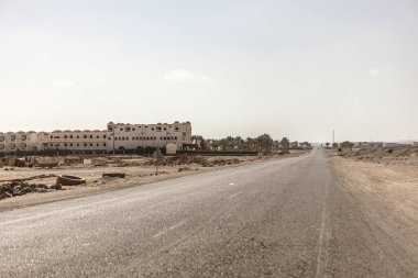 Marsa alam, Mısır 9 Şubat 2025: Issız bir arazide uzanan boş asfalt yol, Marsa alam, Mısır 'da tamamlanmamış, terk edilmiş binalara götürüyor