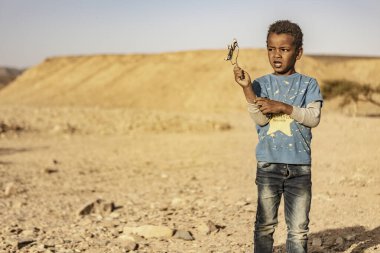 Marsa alam, 9 Şubat 2025: Oyuncak uçak tutan genç bir çocuğun portresi, Marsa Alam, Mısır 'da çöl manzarasında duruyor.