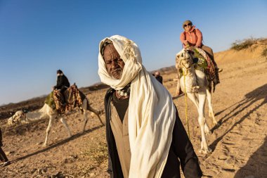 Marsa alam, 9 Şubat 2025: Bedevi rehberi Marsa Alam, Mısır 'da güneşli bir günde çölde bir deve kervanına önderlik ediyor.