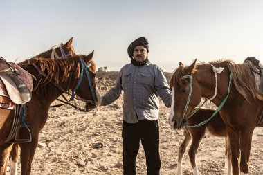 Marsa alam, 9 Şubat 2025: Bedevi adam Marsa Alam, Mısır yakınlarındaki bir çöl arazisinde atlarına ve yavrusuna bakıyor.