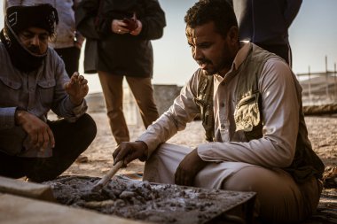 Marsa alam, Mısır 9 Şubat 2025: bedevi adam Marsa alam çölünde tütsü hazırlıyor, Mısır, turistlerle çevrili.