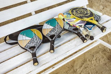 Marsa alam, Mısır 9 Şubat 2025: Marsa Alam, Mısır 'daki bir maçtan sonra renkli plaj tenis raketleri ve topları beyaz bir bankta yatıyor