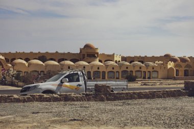 Marsa alam, 9 Şubat 2025: Marsa alam, Mısır 'da kubbeleri ve kemerleri olan, geleneksel Mısır mimarisi yakınlarında güneşli bir gökyüzünün altında park etmiş beyaz kamyonet.