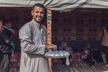 Marsa alam, Mısır 9 Şubat 2025: gülümseyen bedevi adam Marsa alam, Mısır 'da bir çöl çadırında geleneksel çay servisi yapıyor, yerel konukseverlik ve kültür sergiliyor.