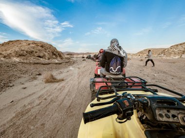 Marsa alam, Mısır 9 Şubat 2025: Bir grup turist açık mavi bir gökyüzü altında, Marsa Alam, Mısırın engebeli çöl manzarasında heyecan verici dört tekerli bisiklet deneyimi yaşıyor