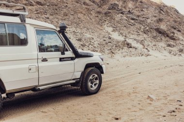 Marsa alam, Mısır 9 Şubat 2025: Mısır 'daki Marsa Alam Çölü' nün kumlu arazisinde yol alan dört tekerlekli beyaz araba maceralı bir çöl safarisi deneyimi sunuyor.
