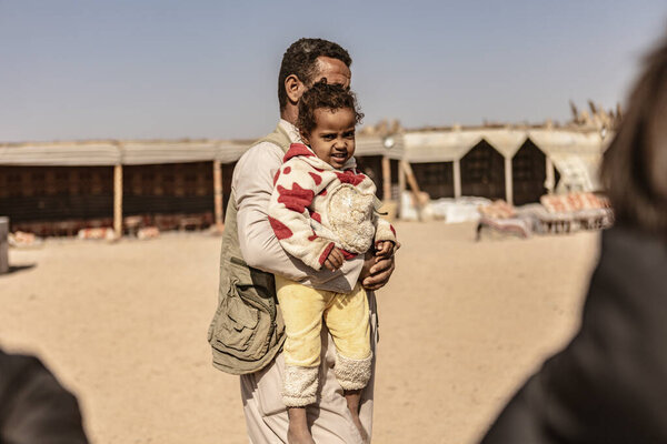 Марса алам, Египет 9 февраля 2025: бедуинский отец, несущий свою маленькую дочь в лагере в пустыне Марса алам, Египет, выражая любовь и заботу