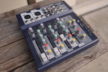 Milan, İtalya, 13 Mart 2025: Bir kompakt ses karıştırıcı ses mühendisliği ve müzik üretimi için hazır, yıpranmış ahşap bir yüzey üzerinde oturur