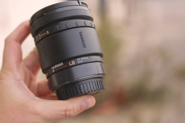 Milan, İtalya 'da 13 Mart 2025: 28-200 mm' lik bir tamron zoom lensini tutan el tasarımı ve işlevselliğini gösteren