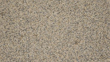 Betona gömülü küçük taşlar ve çakıl taşları, arka plan ve inşaat projeleri için ideal kaba, dokulu bir yüzey oluşturur.