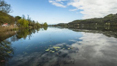 Fimon Gölü 'nün sakin sularının yer aldığı sakin manzara çevredeki ağaçları ve gökyüzünü yansıtıyor ve İtalya' nın veneto bölgesinde barışçıl bir atmosfer yaratıyor.