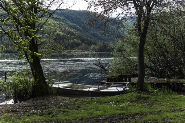 Fimon Gölü kıyısında dinlenen küçük alüminyum tekne, huzurlu bir bahar gününde yemyeşil bitki örtüsüyle çevrili.