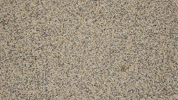 Betona gömülü küçük taşlar ve çakıl taşları, arka plan ve inşaat projeleri için ideal kaba, dokulu bir yüzey oluşturur.