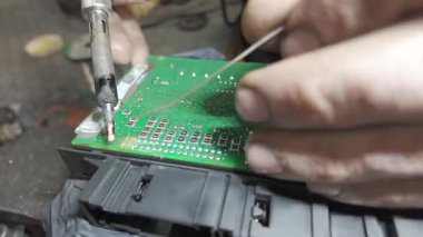 Elektronik bileşenleri devre kartına dikkatlice lehimleyen yetenekli teknisyen, atölye ortamında elektronik tamir konusunda hassasiyet ve uzmanlık gösteriyor.