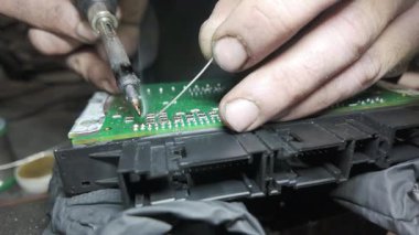 Bir teknisyenin yeşil devre kartına lehimlediği bileşenleri yakından çekerek elektronik onarımında hassasiyet ve uzmanlık gösteriyor.