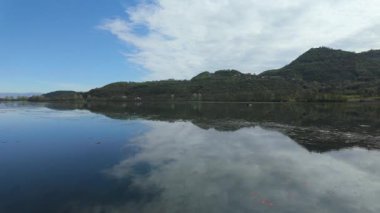 Serene fimon gölü, gök mavisi gökyüzünü yansıtıyor ve yumuşak gün ışığı altında Veneto bölgesinin el değmemiş doğal güzelliğini gözler önüne seriyor.