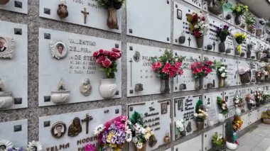 Villanova del ghebbo, İtalya 2 Nisan 2025: Beyaz mermer duvarları süsleyen hatıra plakları, çiçekler ve fotoğraflar Villanova del ghebbo mezarlığında huzurlu bir anıt atmosferi yaratıyor.