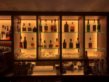 Roma, İtalya, 4 Mayıs 2025: çeşitli alkollü içecekler bir bar tezgahının arkasındaki aydınlatılmış raflarda düzenli olarak düzenlenerek sıcak ve davetkar bir atmosfer yaratılıyor.