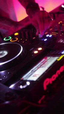 Roma, İtalya 4 Mayıs 2025: Pembe ışıklandırmalı bir gece kulübünde öncü bir kontrolörde DJ 'in müziği karıştırması