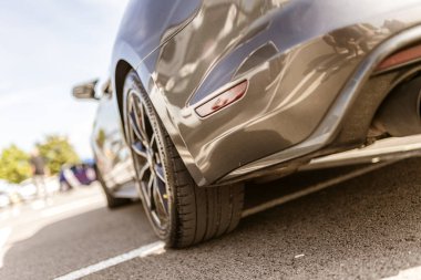 Roma, İtalya 4 Mayıs 2025: arka tekerin alçak açılı görüntüsü, egzoz borusu, ve park yerinde park edilmiş modern gri spor bir arabanın kenarı.