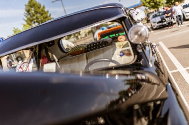 Roma, İtalya, 4 Mayıs 2025: Güneşe parlayan siyah klasik araba, gökyüzünü ve çevresindeki manzarayı yansıtıyor, iç mekan eski ayrıntılar ve yastıklarla görülebilir.