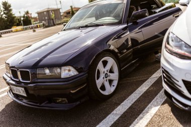 Roma, İtalya 4 Mayıs 2025: Koyu mavi BMW E36 üstü açık bir park yerine park edilmiş, kapısı açık, içerisi de açık.