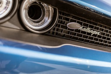 Roma, İtalya, 4 Mayıs 2025: mavi Dodge meydan okuyucusunun ön ızgarasının ve farının yakın çekimi, ikonik meydan okuyucu rozetini vurguluyor