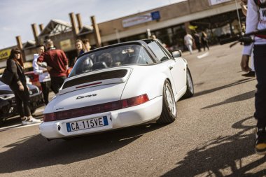 Roma, İtalya 4 Mayıs 2025: beyaz Porsche Carrera Cabriolet bir otoparka park edilmiş ve insanlar lüks spor arabaya hayran.