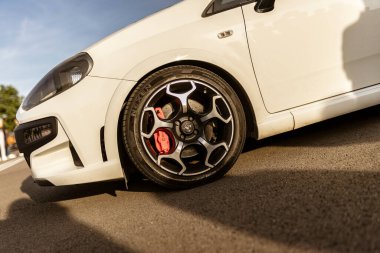 Roma, İtalya 4 Mayıs 2025: asfalta park etmiş beyaz bir spor arabanın yakın çekimi, alaşımlı tekerleği, kırmızı fren kalibreli ve düşük profilli lastiği vurguluyor.