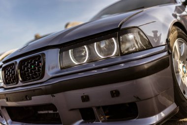 Roma, İtalya 4 Mayıs 2025: açık havada park etmiş gri bir BMW E36 'nın önünde, melek gözleri farlarına ve özelleştirilmiş ızgaralara odaklanıyor.