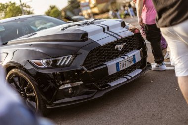 Roma, İtalya 4 Mayıs 2025: siyah Ford Mustang, beyaz yarış çizgileri asfalta park edilmiş, alaşımlı tekerlekleri ve ön ızgarayı gösteriyor.