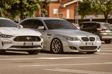Roma, İtalya 4 Mayıs 2025: gümüş BMW ve beyaz Ford Mustang yan yana park edilmiş asfalt bir otoparkta.