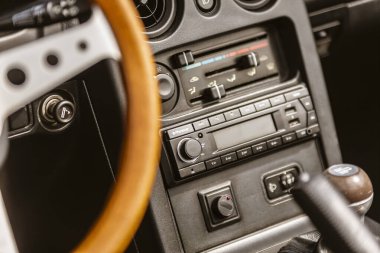 Roma, İtalya, 4 Mayıs 2025: Öncü stereo sistemi, iklim kontrol düğmeleri ve klasik iç tasarımı ön plana çıkaran ahşap direksiyon tekerleği içeren klasik bir arabanın ön paneli