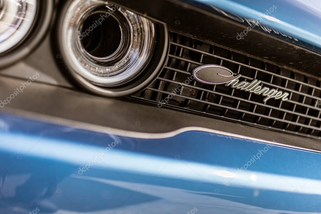 Rome, italy 4 may 2025: close-up of a blue dodge challenger's front grill and headlight, highlighting the iconic challenger badge