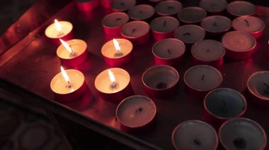 Kilisede metal bir tepside dizilmiş pek çok küçük yanan adak mumları sıcak ve ruhani bir atmosfer yaratıyor.