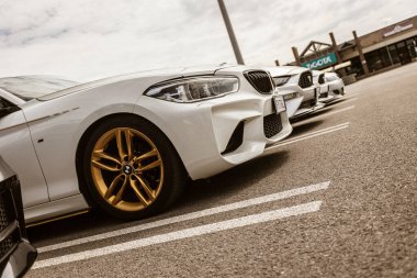 Roma, İtalya 4 Mayıs 2025: Altın jantlı şık beyaz BMW M2, diğer spor arabaların yanına park edilmiş, otomotiv zarafeti ve performansı sergileniyor