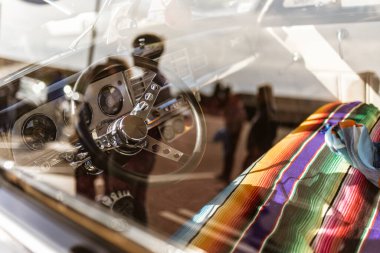 Güneş ışığı, klasik bir arabanın koltuğuna örtülmüş canlı bir Meksika battaniyesini vurguluyor. Klasik stil ve işçiliğin güzelliğini gözler önüne seriyor.